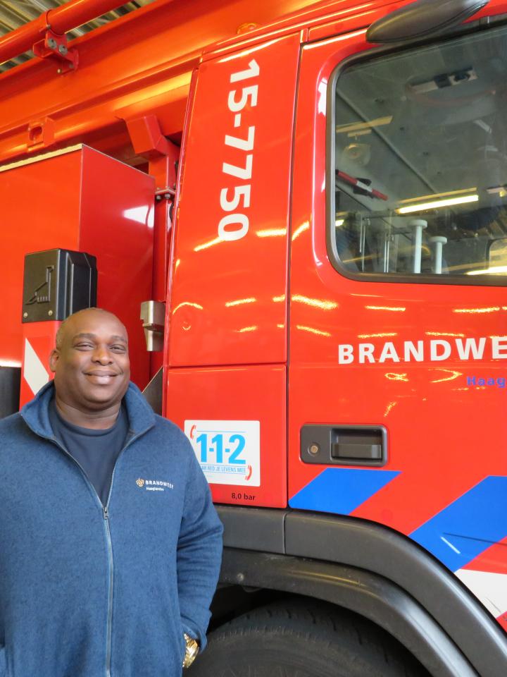 Surinaamse brandweercollega Olton Pinas poseert voor brandweerwagen