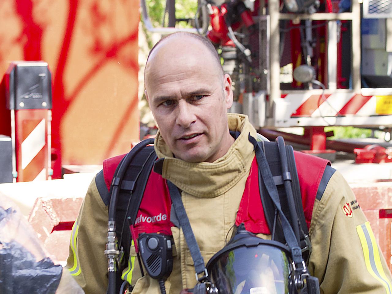 Brandweerman Marinus van Dam in bluspak houdt helm vast