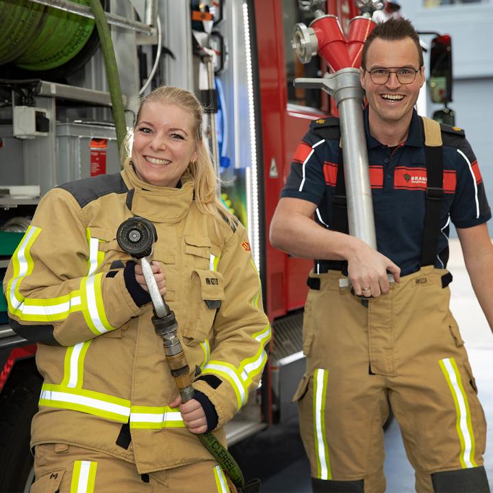 Brandweervrijwilligers Danny en Jessica poseren met brandweermaterieel