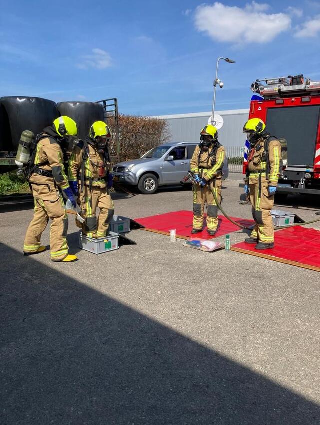 Brandweermensen maken elkaar schoon na een oefening van een incident met gevaarlijke stoffen