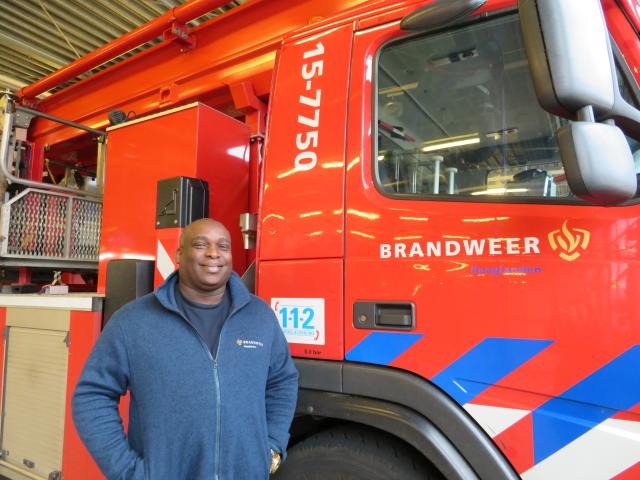 Surinaamse brandweercollega Olton Pinas poseert voor brandweerwagen